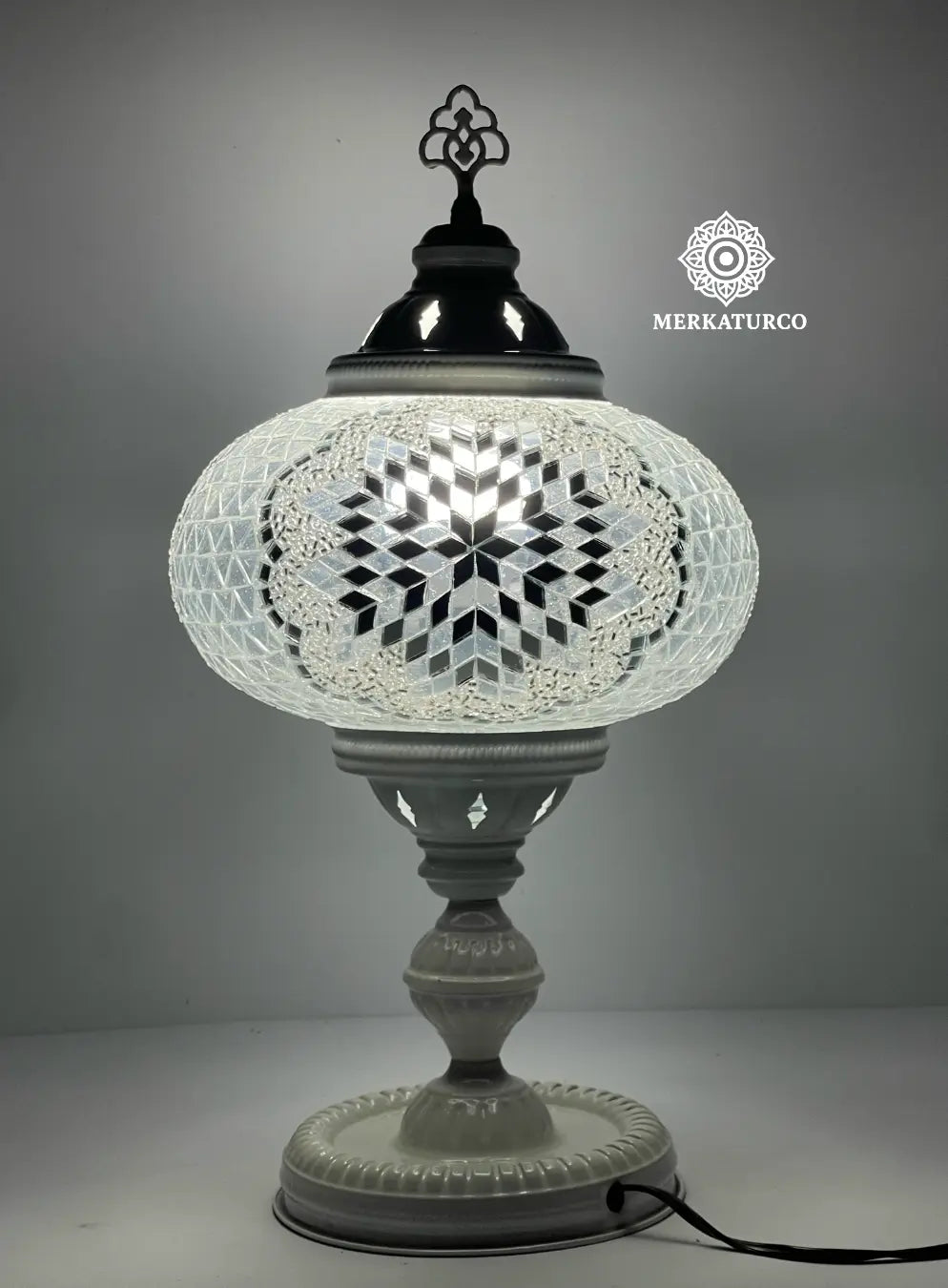 Lámpara turca de mesa encendida, reflejando tonos cálidos a través del mosaico espejado artesanal.